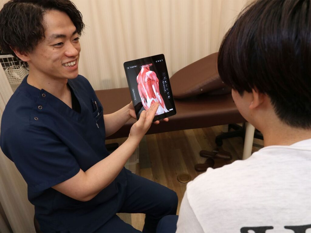 からだラボ整骨院の施術者が、タブレットの筋肉の図を使って体の状態を説明している様子