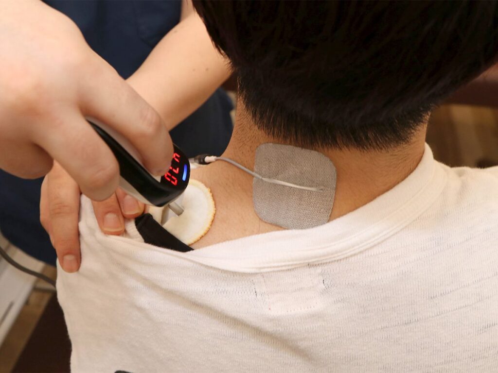 溝の口のからだラボ整骨院で、首まわりの筋肉に電気の機器をあてて施術している様子